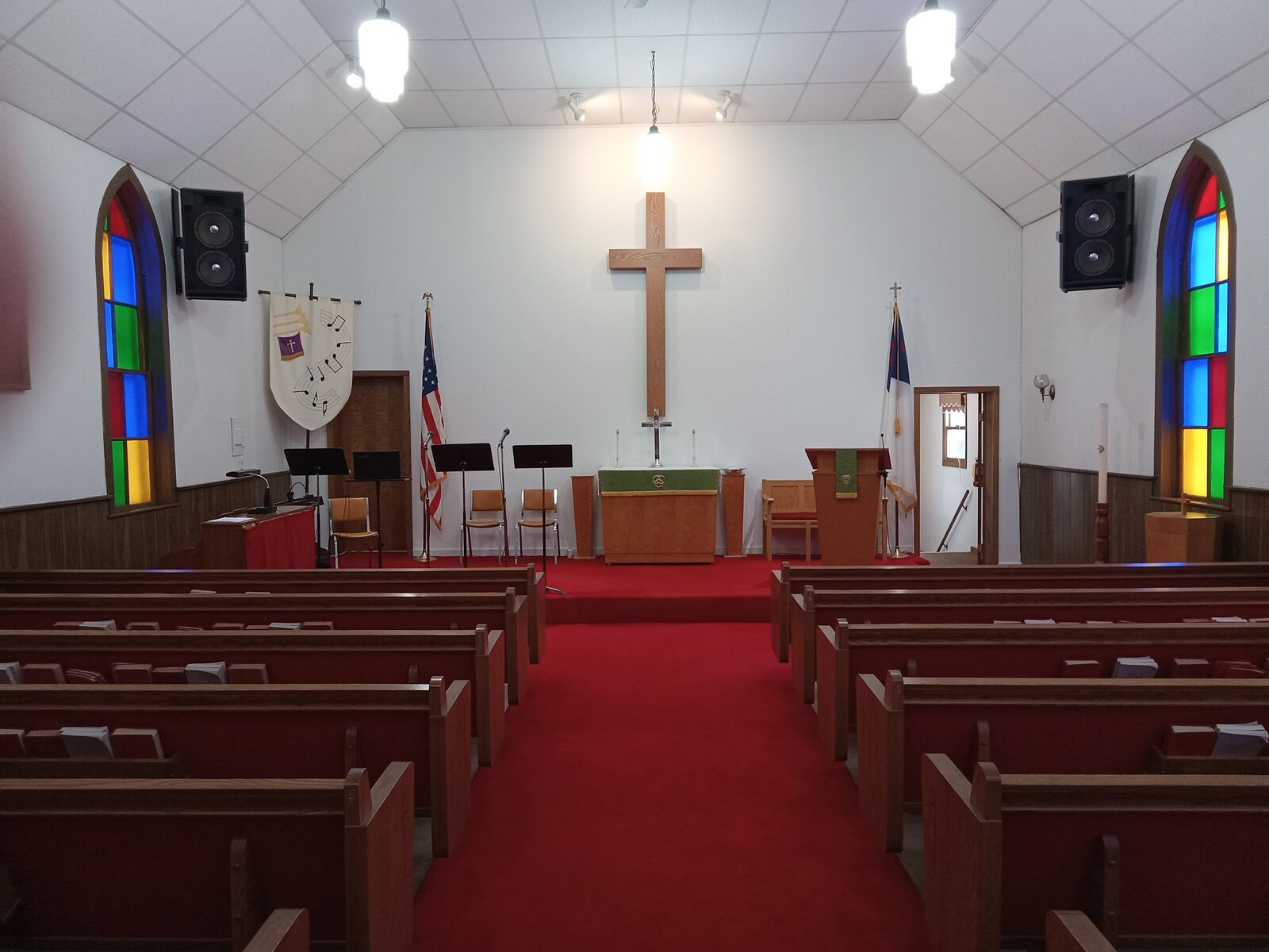 The sanctuary of United Lutheran Church, with red carpet, wooden pews, stained-glass windows, and a wooden cross at the altar